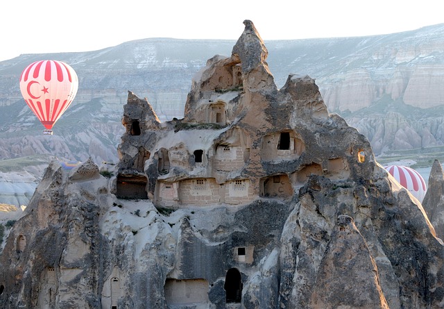 Concrete rock structure with a Hot air balloon flying by the rock's structure.