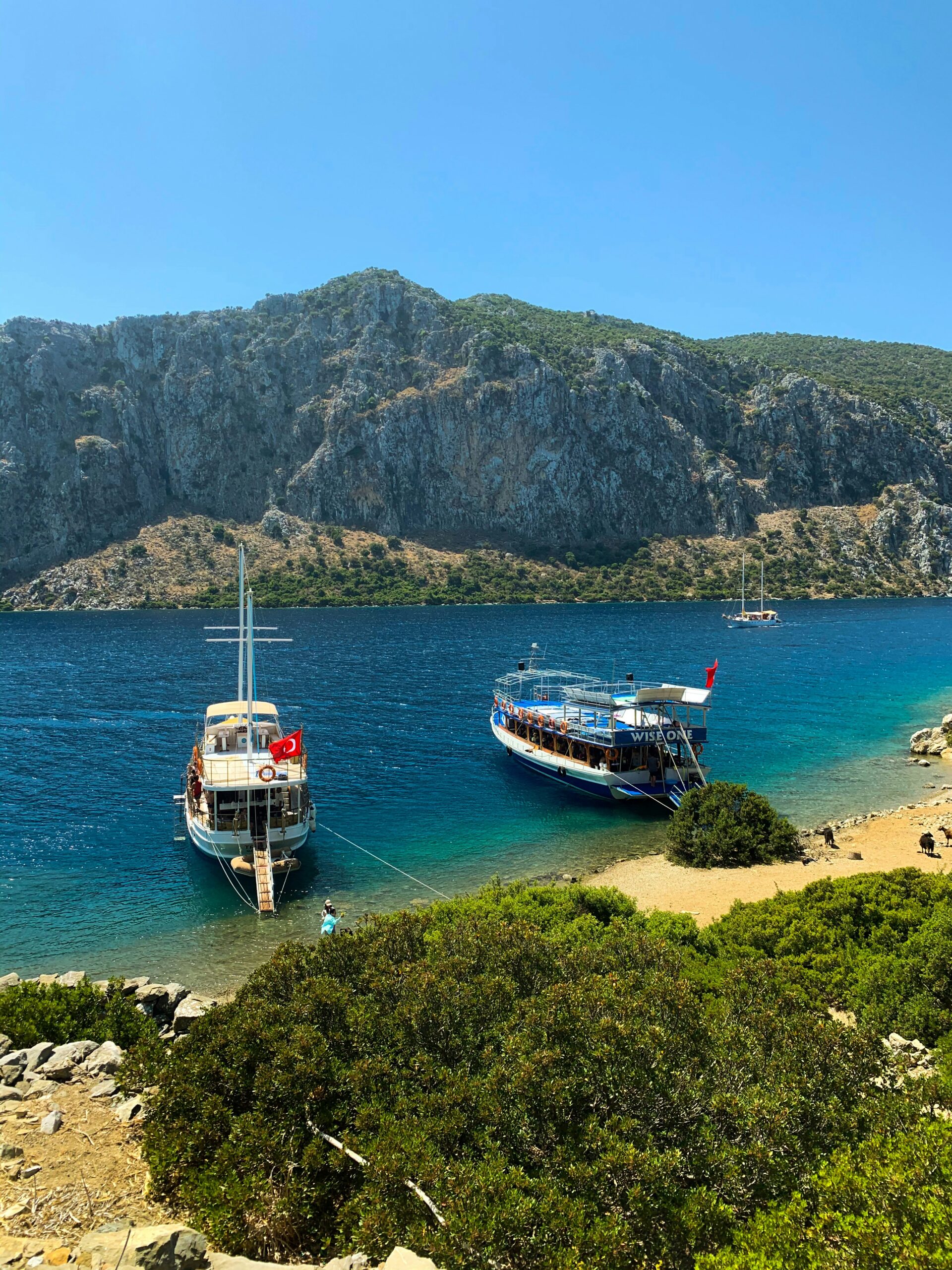 Red and white boat on sea near mountains during daytime.