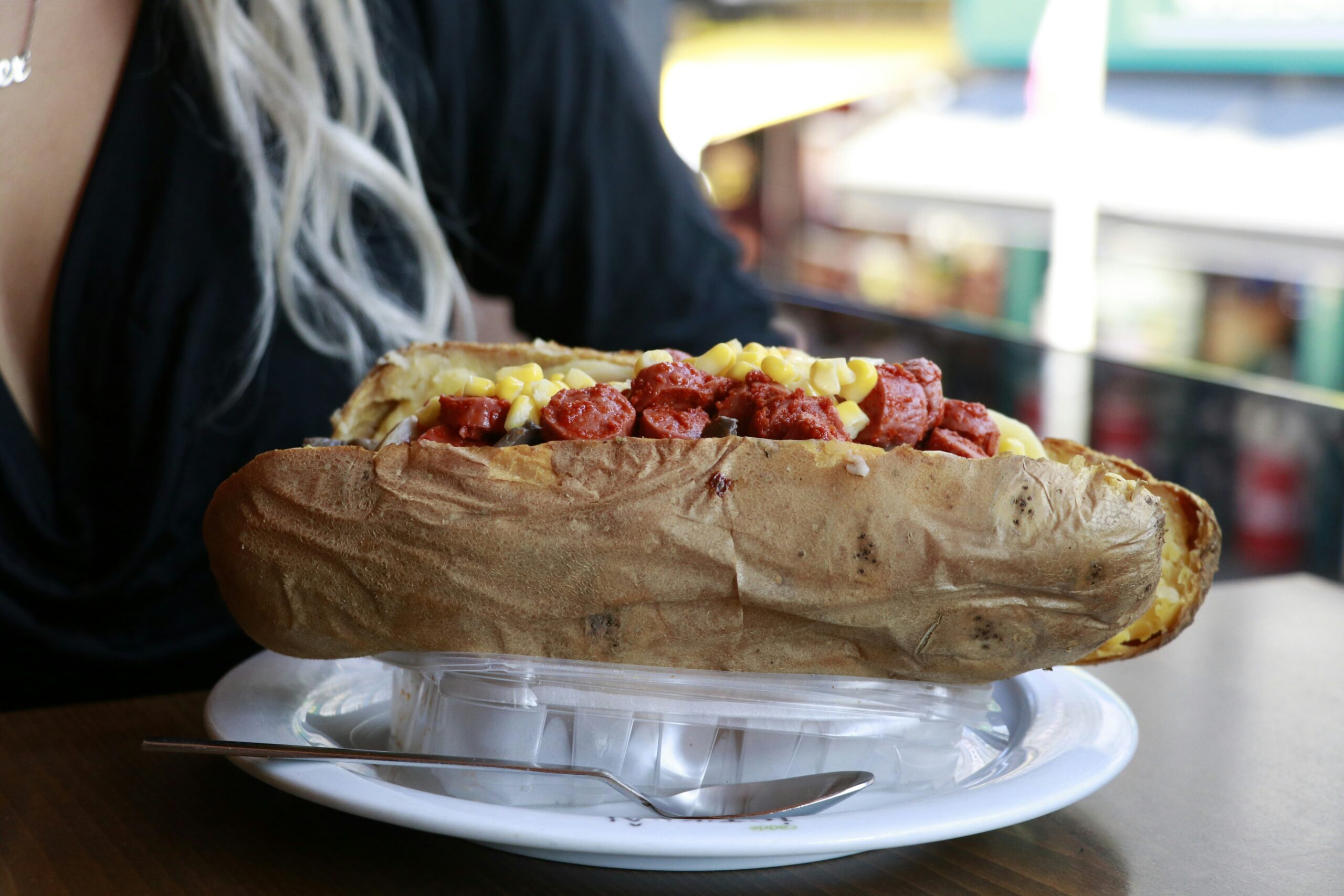 Photo of a person sitting at a table with a plate of Kumpir ( famous Istanbul street food)