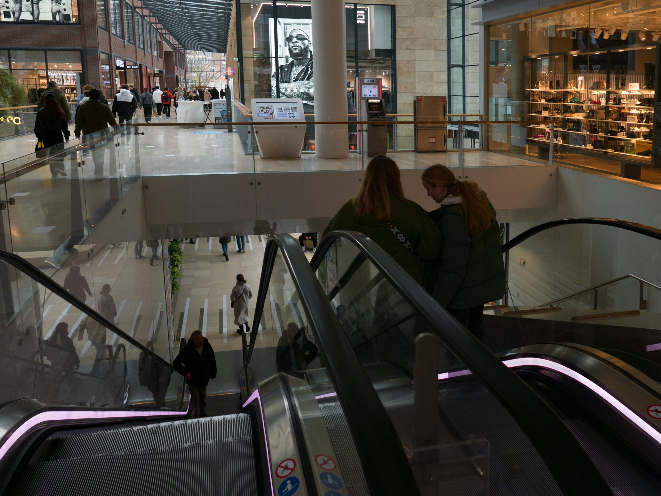 couple of people riding down an escalator